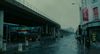 A grey, rainy urban street. An electronic billboard in the background reads 'avoiding fertility tests is a crime'
